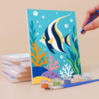 Painting a Reef Friends mini canvas propped up beside numbered acrylic paints