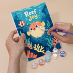 Hand holding a Reef Joy mini canvas while painting the details