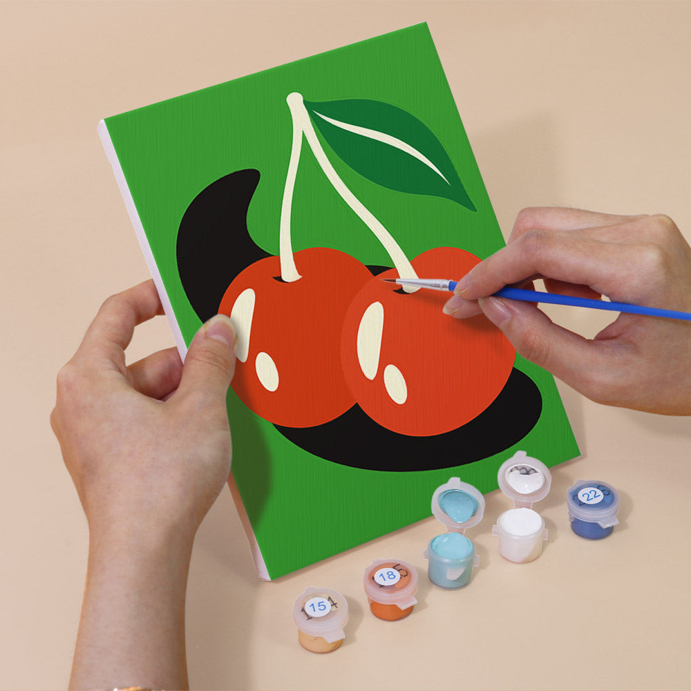 Hand holding a Retro Charms mini canvas while painting the details