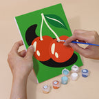 Hand holding a Retro Charms mini canvas while painting the details