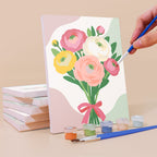 Painting a Ribbon Bouquets mini canvas propped up beside numbered acrylic paints