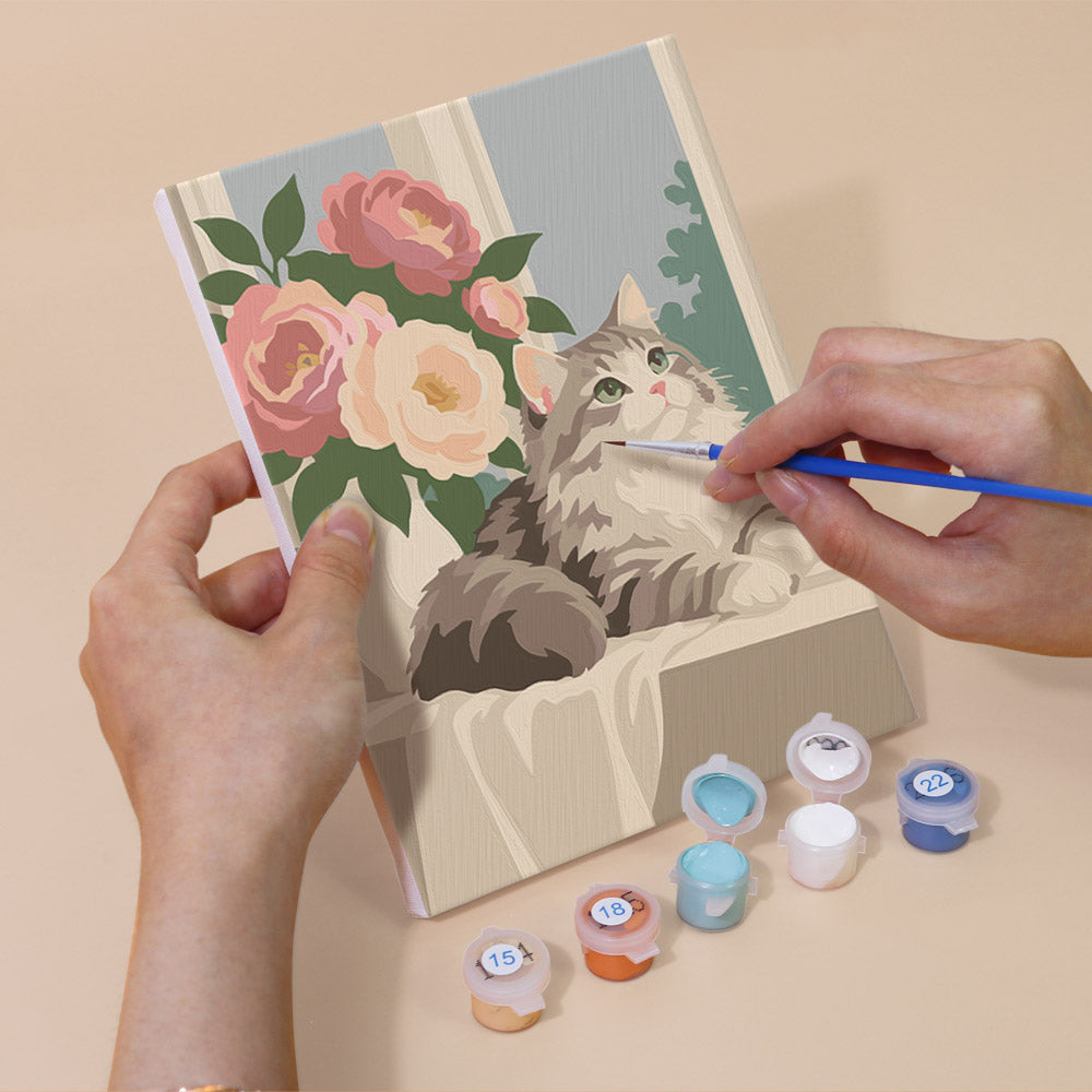 Hand holding a Roses and Whiskers mini canvas while painting the details