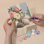 Hand holding a Roses and Whiskers mini canvas while painting the details