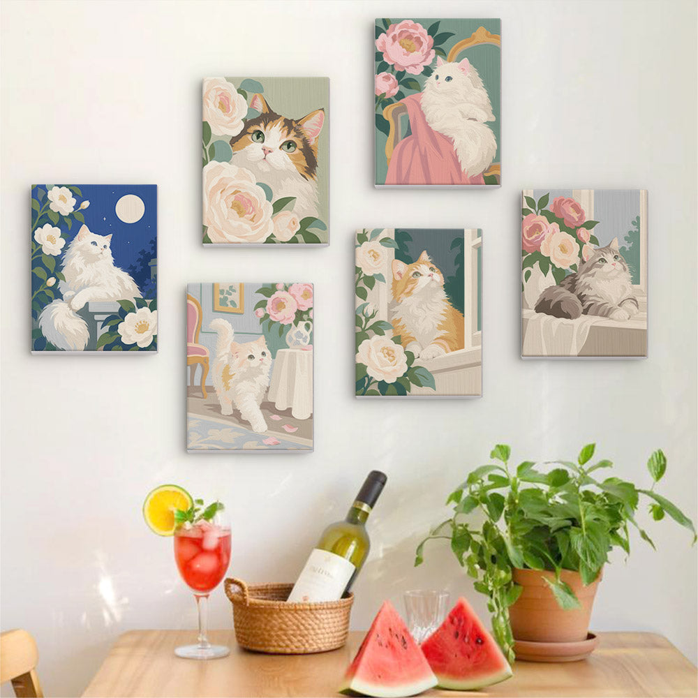 Six finished Roses and Whiskers mini paintings hung on a wall above a table