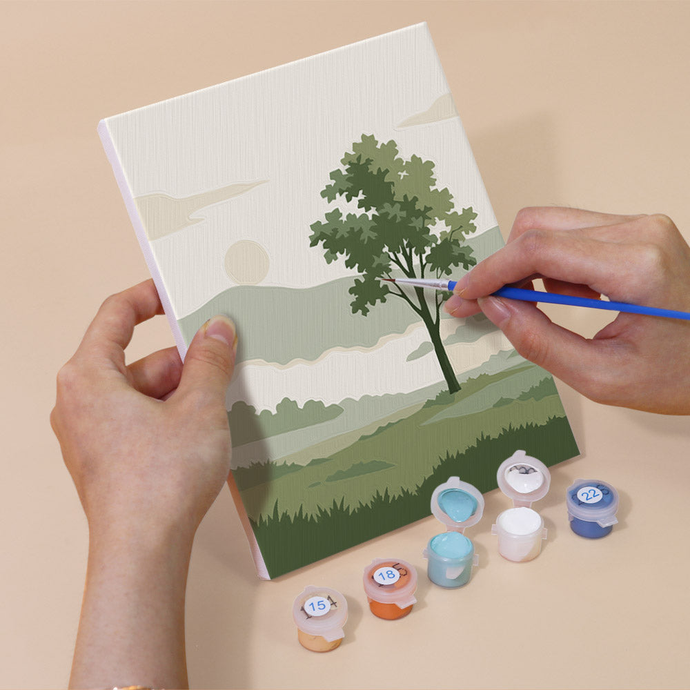Hand holding a Sage Horizons mini canvas while painting the details
