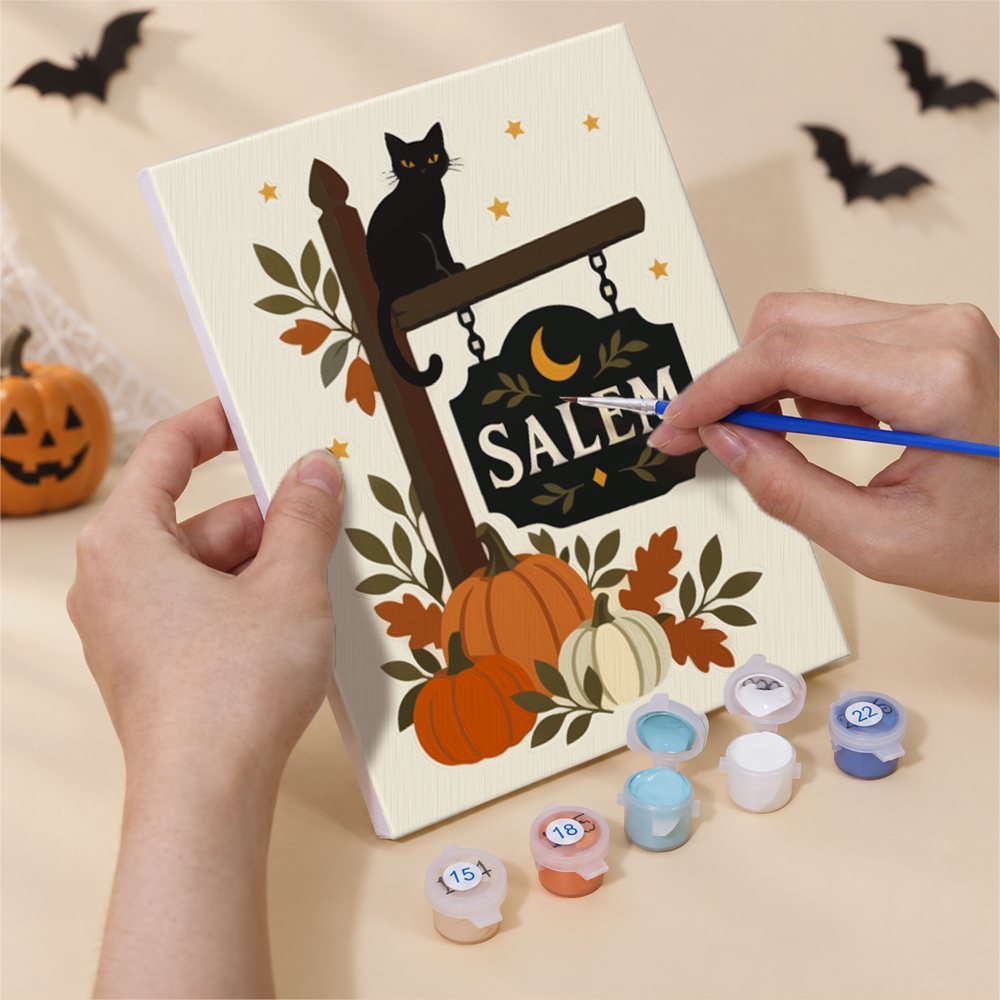 Hand holding a Salem Black Cat Autumn mini canvas while painting the details