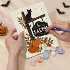 Hand holding a Salem Black Cat Autumn mini canvas while painting the details