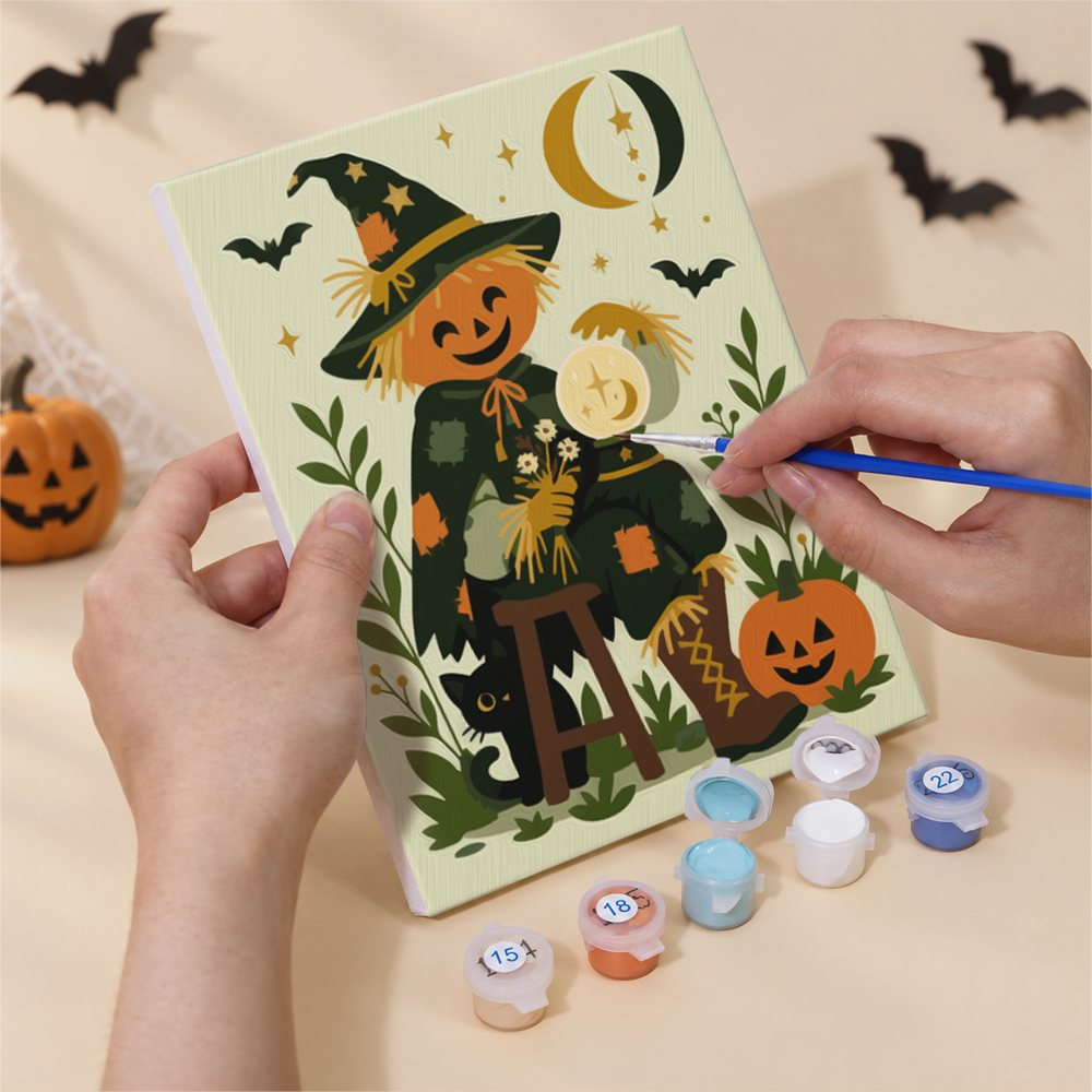 Hand holding a Scarecrow Harvest Friends mini canvas while painting the details