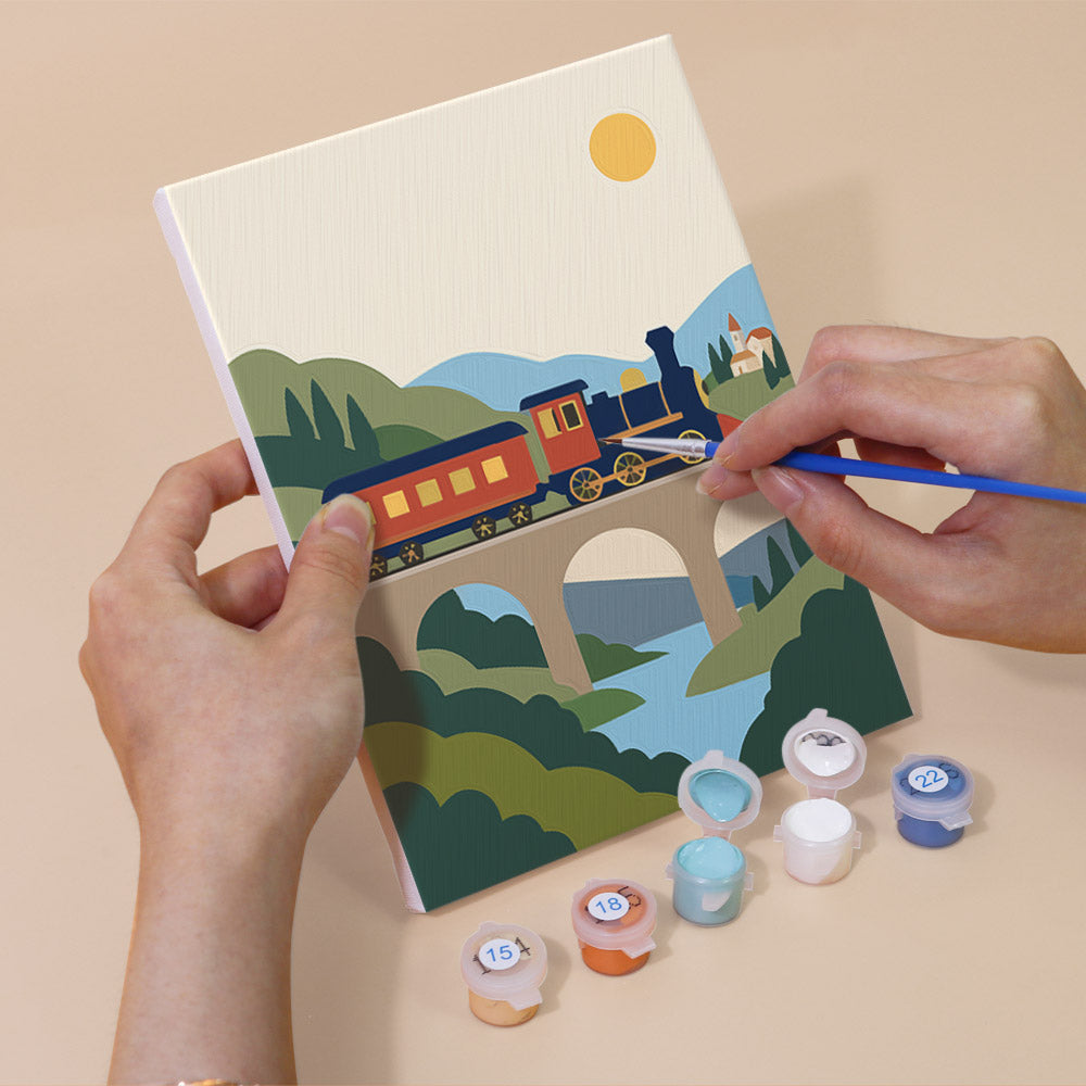 Hand holding a Scenic Rides mini canvas while painting the details