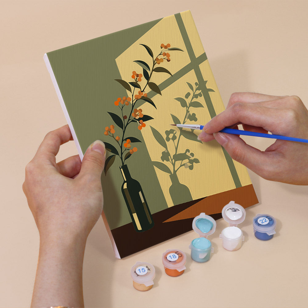 Hand holding a Shadow and Stems mini canvas while painting the details