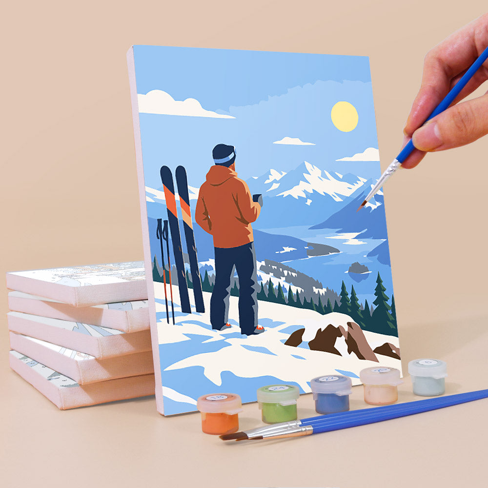 Painting a Snow Day Skiers mini canvas propped up beside numbered acrylic paints