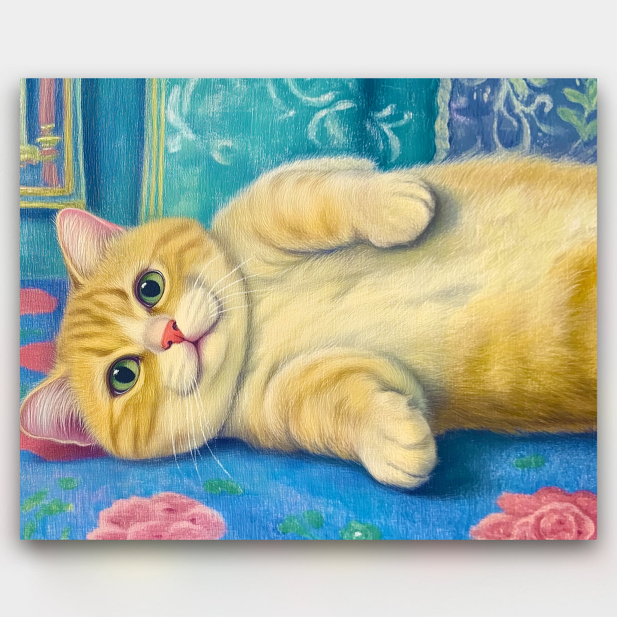 Painting of a yellow cat lying on a blue surface with floral patterns