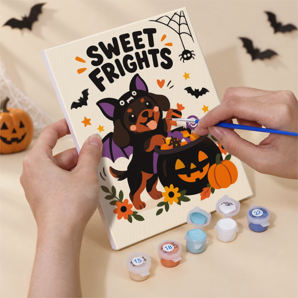Hand holding a Spooky Cutie Sayings mini canvas while painting the details