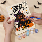 Hand holding a Spooky Cutie Sayings mini canvas while painting the details