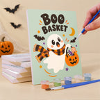 Painting a Spooky Cutie Sayings mini canvas propped up beside numbered acrylic paints