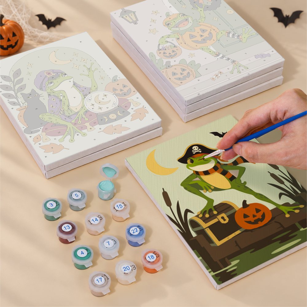 Painting one of the Spooky Frog Masquerade designs next to a stack of mini canvases