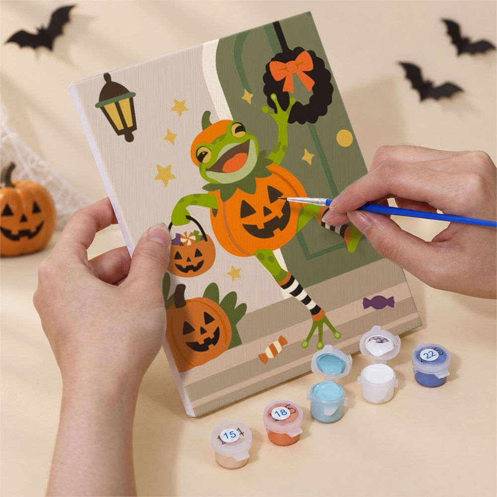 Hand holding a Spooky Frog Masquerade mini canvas while painting the details