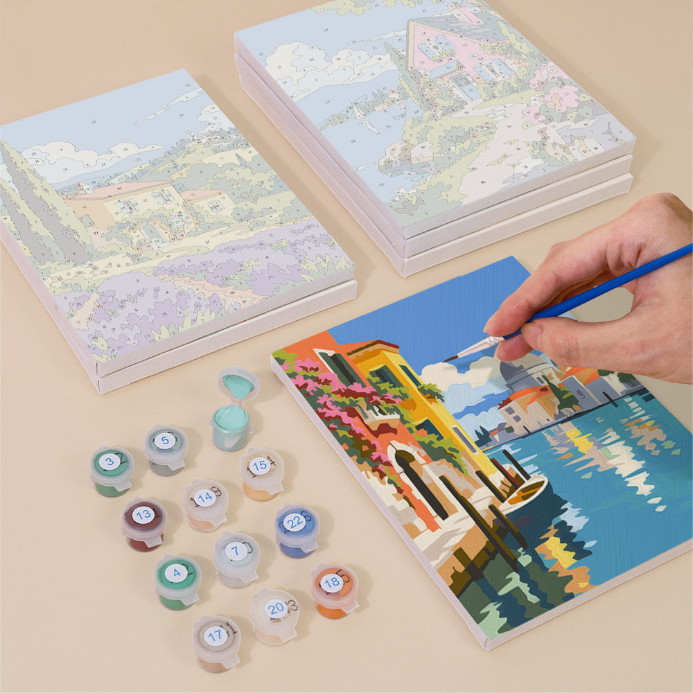 Painting one of the Storybook Villages designs next to a stack of mini canvases