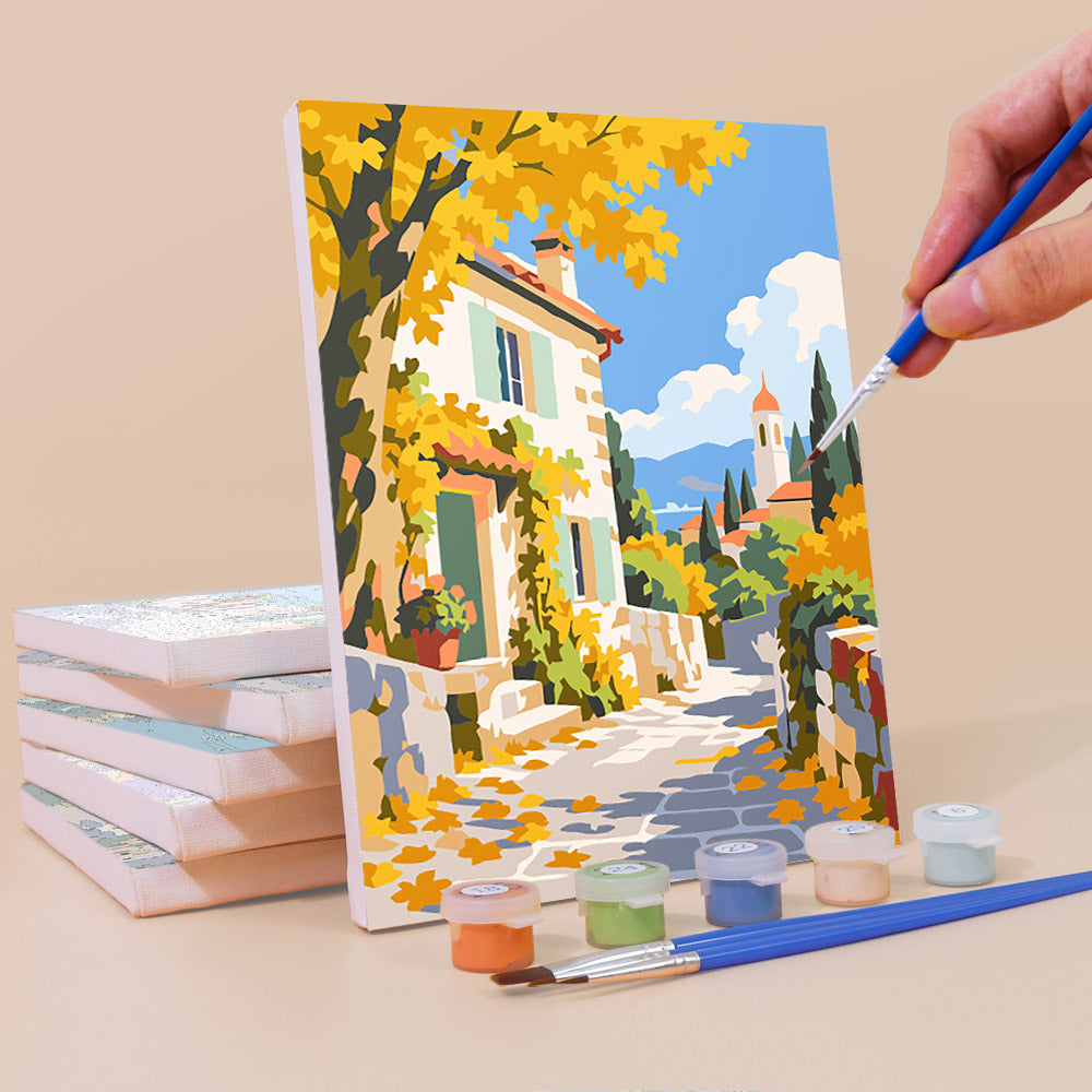Painting a Storybook Villages mini canvas propped up beside numbered acrylic paints