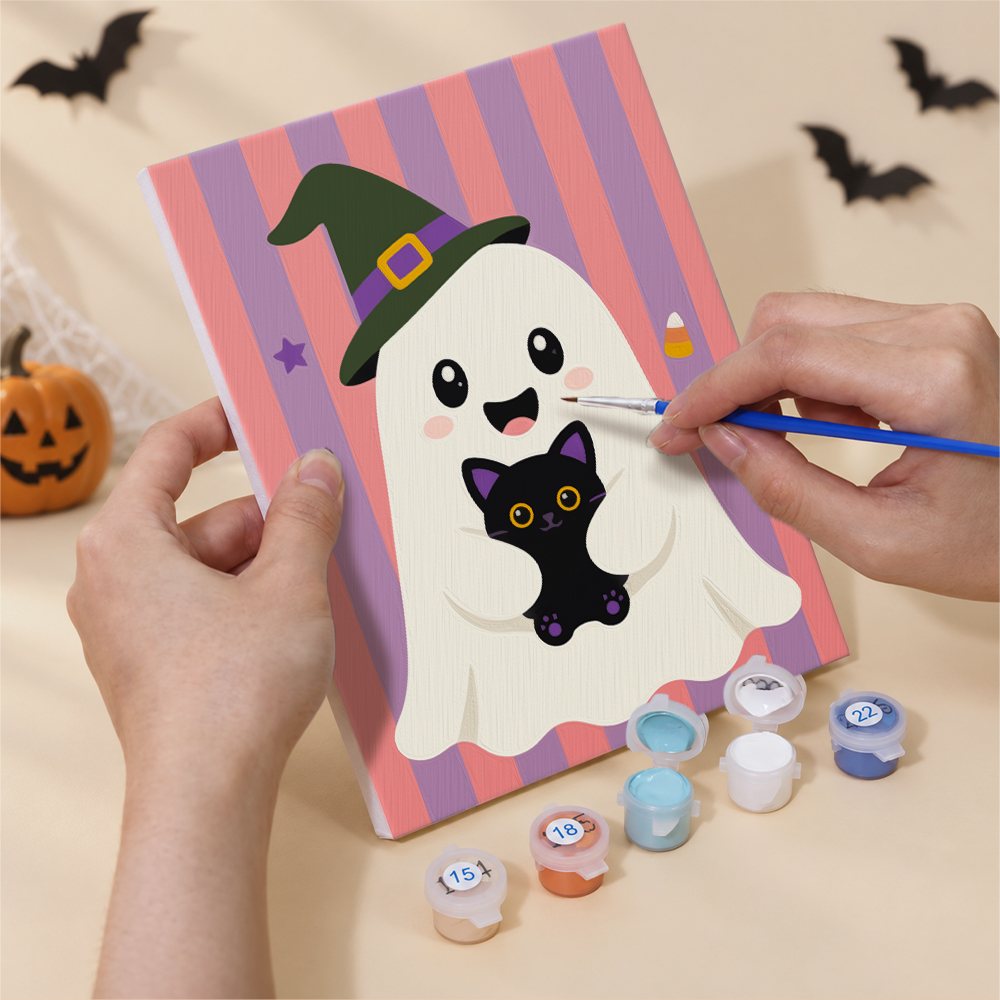 Hand holding a Striped Ghosties mini canvas while painting the details