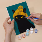 Hand holding a Style Critters mini canvas while painting the details
