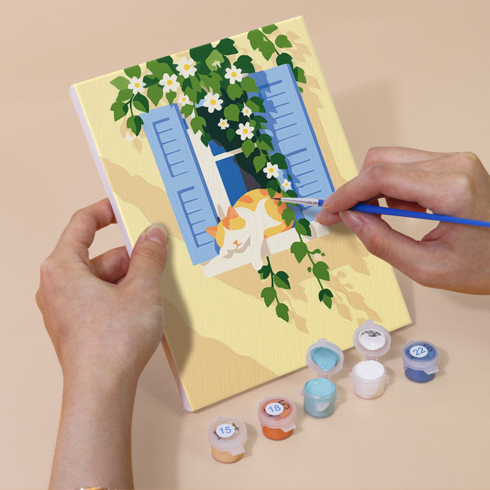 Hand holding a Summer Escapes mini canvas while painting the details
