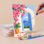 Painting a Summer Escapes mini canvas propped up beside numbered acrylic paints