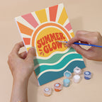 Hand holding a Summer Glow mini canvas while painting the details