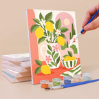 Painting a Summer Glow mini canvas propped up beside numbered acrylic paints