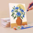 Painting a Sunlit Bouquets mini canvas propped up beside numbered acrylic paints