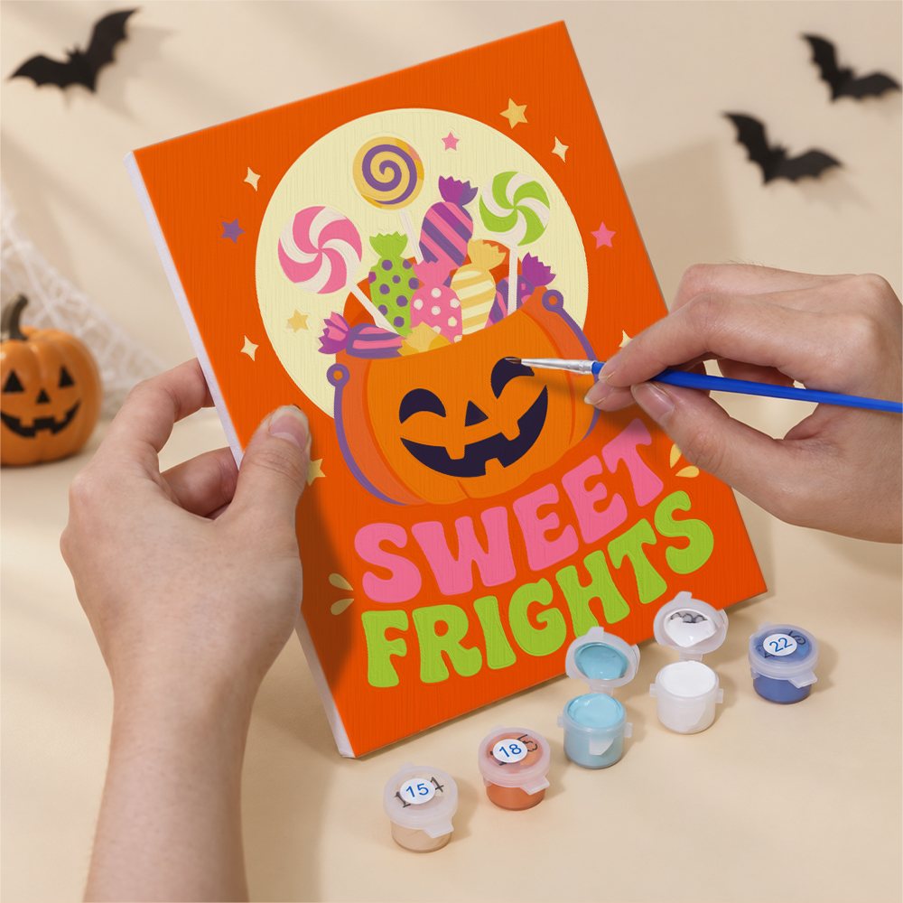 Hand holding a Sweet Frights mini canvas while painting the details