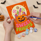 Hand holding a Sweet Frights mini canvas while painting the details