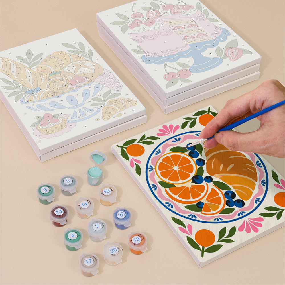 Painting one of the Tablecloth Treats designs next to a stack of mini canvases