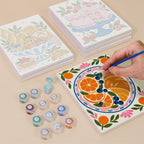 Painting one of the Tablecloth Treats designs next to a stack of mini canvases