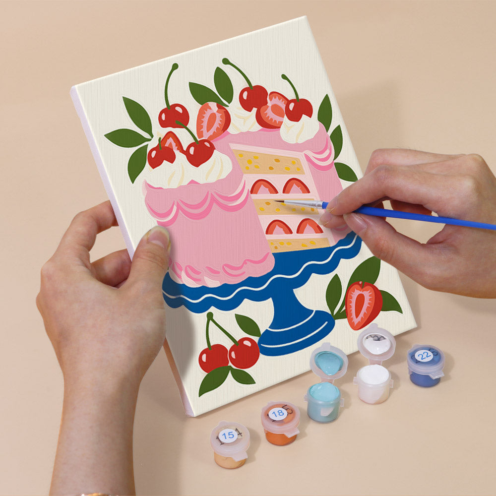Hand holding a Tablecloth Treats mini canvas while painting the details