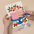 Hand holding a Tablecloth Treats mini canvas while painting the details