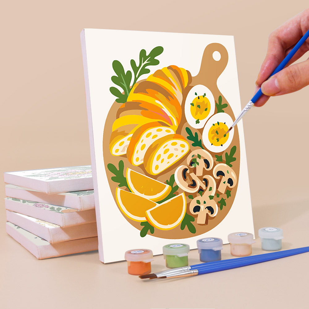 Painting a Tablecloth Treats mini canvas propped up beside numbered acrylic paints