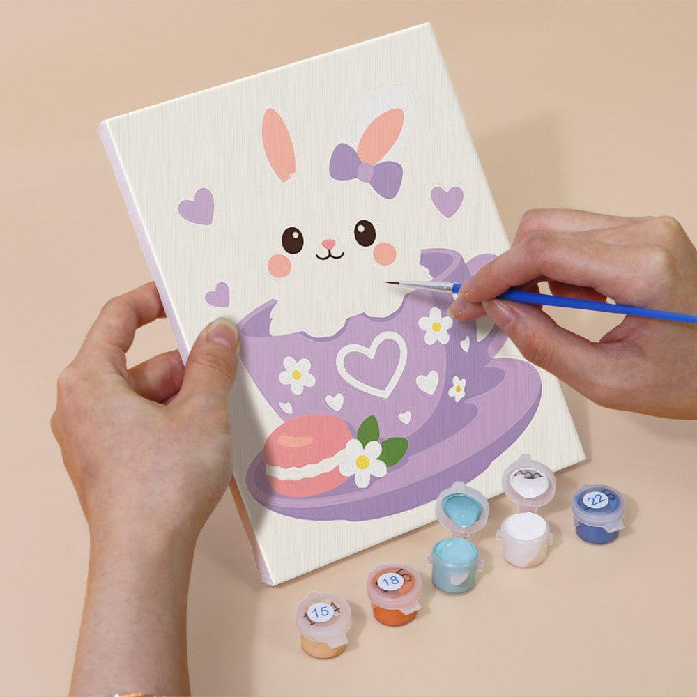 Hand holding a Teacup Critters mini canvas while painting the details