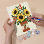 Hand holding a Tin Can Bouquets mini canvas while painting the details
