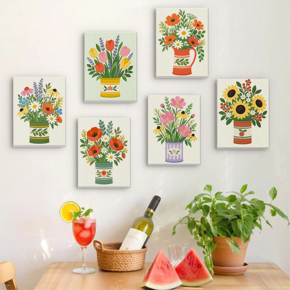 Six finished Tin Can Bouquets mini paintings hung on a wall above a table