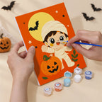 Hand holding a Tiny Trick-or-Treaters mini canvas while painting the details