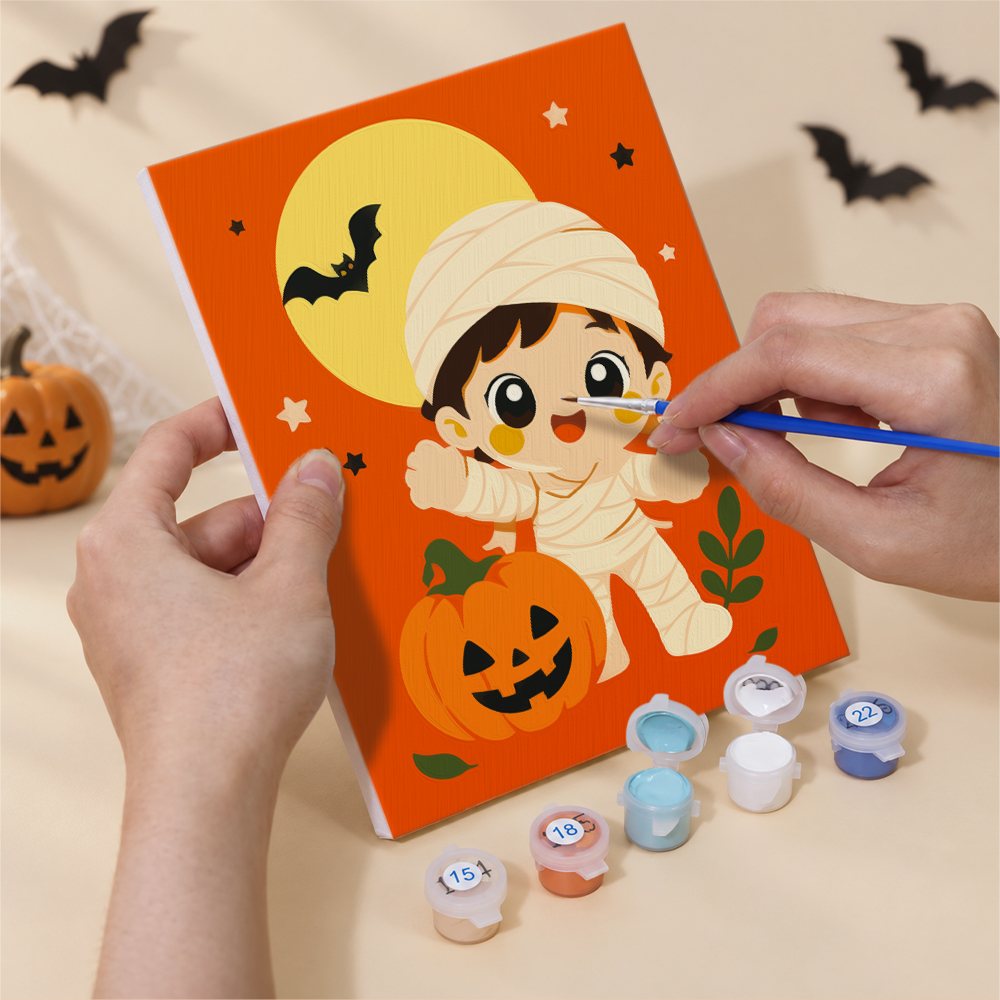 Hand holding a Tiny Trick-or-Treaters mini canvas while painting the details