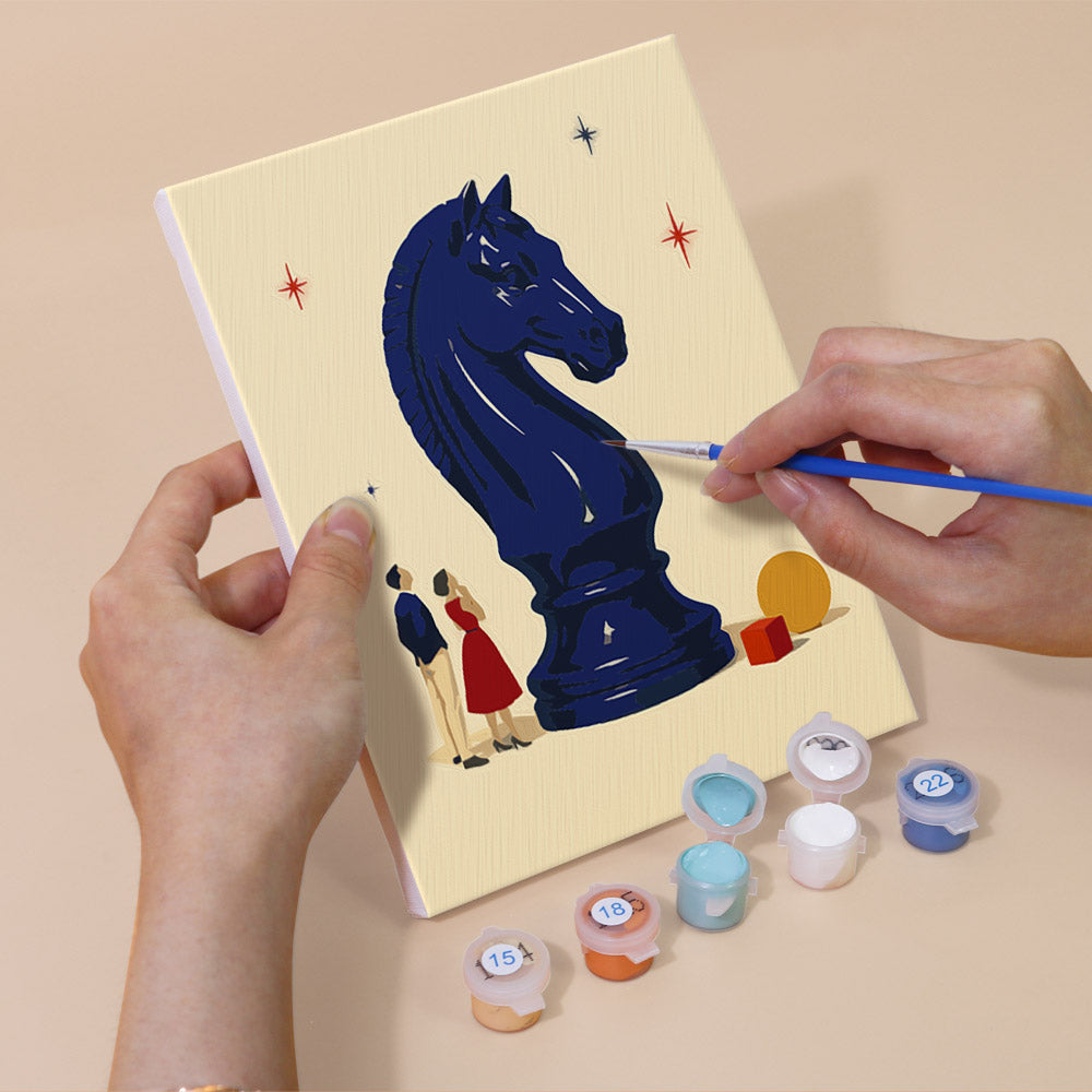Hand holding a Tiny Worlds mini canvas while painting the details