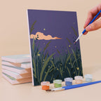 Painting a Twilight Meadows mini canvas propped up beside numbered acrylic paints
