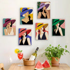 Six finished Wide-Brim Glamour mini paintings hung on a wall above a table