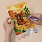 Hand holding a Wild West Nights mini canvas while painting the details