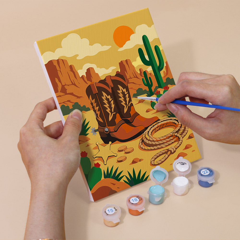 Hand holding a Wild West Nights mini canvas while painting the details