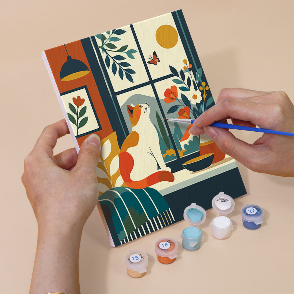 Hand holding a Window Cats mini canvas while painting the details