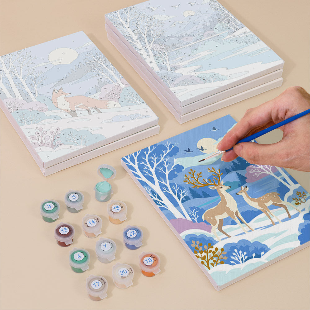 Painting one of the Winter Wonderland designs next to a stack of mini canvases