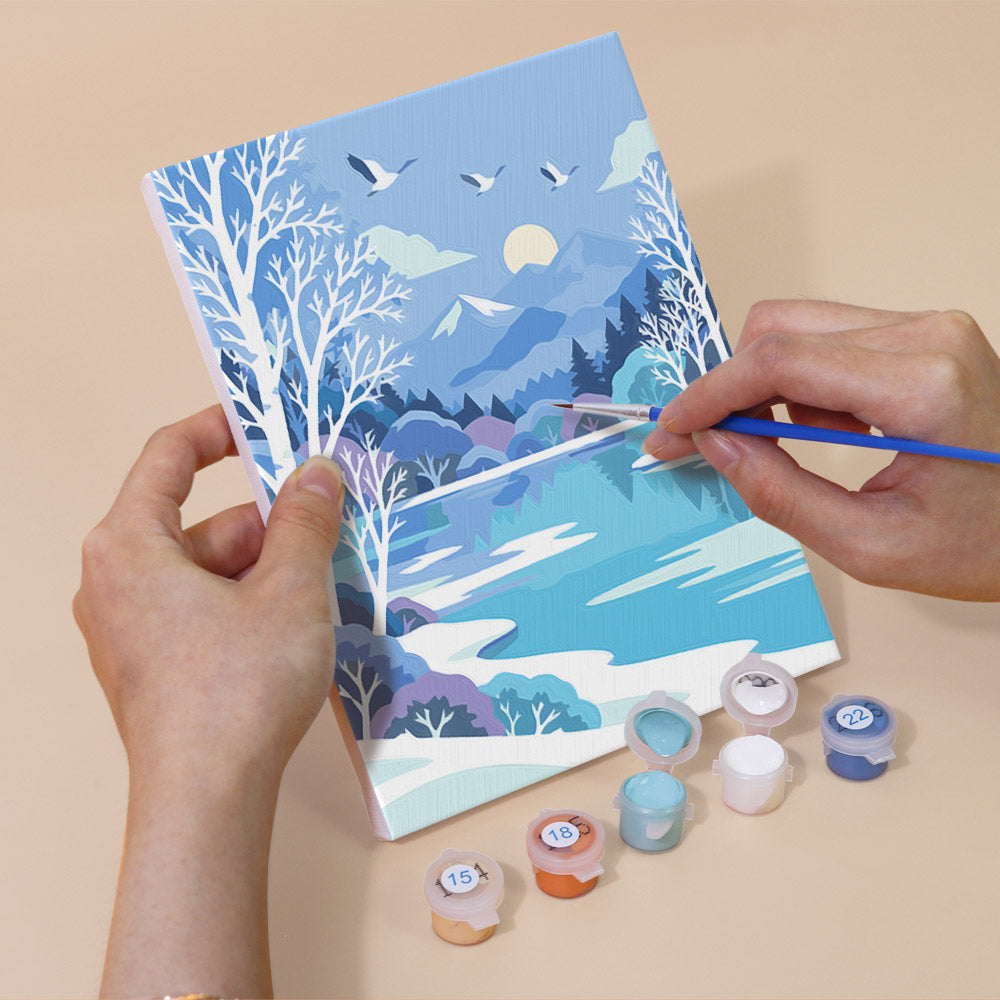 Hand holding a Winter Wonderland mini canvas while painting the details